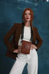 Phonebag pequeña color mostaza, confeccionada en cuero sintético, con solapa frontal y correa ajustable con logo de la marca.