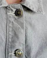 Sobrecamisa de denim azul con cuello camisero, cierre frontal con botones, mangas largas con puños abotonados y dos bolsillos con solapa en el pecho.