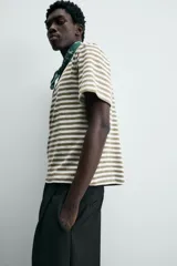 Camiseta de manga corta con cuello redondo y calce relajado, confeccionada en tejido de rayas horizontales blancas y negras.