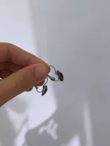 Caravanas con diseño de ojo turco circular, con centro negro rodeado de anillos en tonos azul y blanco, montadas en base de acero quirúrgico con cierre tipo gancho.