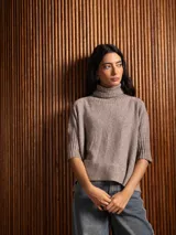 Poleron negro de tejido de punto con cuello alto doble y mangas 3/4 con puños acanalados.