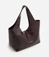 Cartera shopper grande Satinato de poliuretano color bordó con acabado brillante, diseño amplio de trapecio invertido y asas anchas para llevar al hombro.