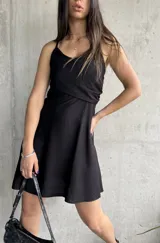 Vestido corto negro con breteles finos y escote cruzado.