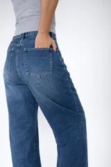 Pantalón de jean con corte balloon fit, de tiro alto y diseño holgado en las piernas. Confeccionado en denim con elastano, presenta un lavado azul clásico y cierre frontal con botón y cremallera.