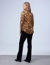 Blusa de seda fría con estampado animal print en tonos marrones. Tiene cuello redondo con escote en V y aro metálico decorativo.