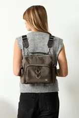 Bandolera convertible en mochila, color negro, con múltiples bolsillos externos con cierre, manija superior y correas regulables y extraíbles.