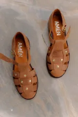 Sandalias de cuero vacuno color negro, estilo cangrejera, con diseño cerrado de tiras entrelazadas, tachas metálicas decorativas, tira con hebilla lateral ajustable y taco bajo.