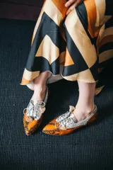 Zapato blucher de cuero con estampado animal print en tonos naranja y plateado, con cordones y detalle de borlas.