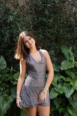 Vestido corto color fucsia con escote en V, breteles finos que se atan al cuello, corte a la altura de la cadera y falda acampanada con ruedo irregular.