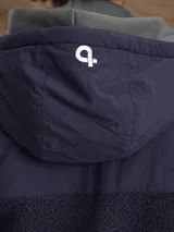 Campera con capucha confeccionada en una combinación de tejido técnico y sherpa, con cierre frontal completo y puños elásticos.