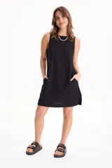 Vestido corto negro sin mangas, de corte recto y holgado, con cuello redondo y bolsillos laterales invisibles.