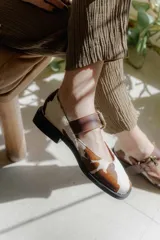 Zapatos tipo Mary Jane con punta cuadrada, confeccionados en cuero con estampado de vaca (animal print) y tira ajustable con hebilla metálica en color marrón.