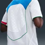 Camiseta deportiva Nike Total 90 Energy de manga corta, color blanco con detalles en dorado, verde, azul y rojo. Presenta un diseño de paneles curvos, cuello en V tricolor y el gráfico distintivo '90' en el centro del pecho.