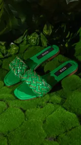 Sandalias negras con tiras trenzadas y cadena dorada.