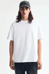 Remera blanca de manga corta, cuello redondo ribeteado y corte relajado con hombros caídos. Fabricada en punto liviano con fibra COOLMAX.
