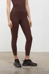 Calza deportiva de tiro alto color marrón espresso, confeccionada en tejido suave y elastizado con compresión media. Presenta un diseño sin costuras en el frente, largo 3/4 y terminaciones con corte láser en las piernas.