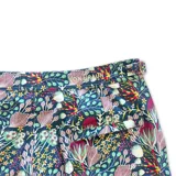 Short de baño con estampado floral y botánico en tonos violeta, rosa y verde sobre fondo oscuro. Presenta pretina fija con hebillas metálicas laterales para ajuste, cierre frontal con botón a presión, bolsillos laterales y bolsillo trasero.