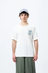 Remera blanca de corte amplio con mangas cortas y estampado de una postal con una palmera y el mar.