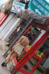 Vestido corto de tejido de punto color beige, con escote profundo tipo halter y falda con volados en el frente.