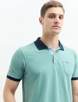 Remera manga corta color verde con cuello polo y bolsillo en el pecho. El cuello y los puños son de color azul marino.