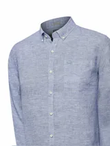 Camisa de manga larga para hombre, confeccionada en lino orgánico color azul con textura suave. Tiene cuello abotonado, bolsillo en el pecho con logo bordado y detalles en contraste en el interior.