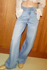 Jeans de tiro alto con diseño de pierna extra ancha y larga. Presenta cinco bolsillos, cierre frontal con cremallera y botón metálico, con un acabado de lavado desgastado.