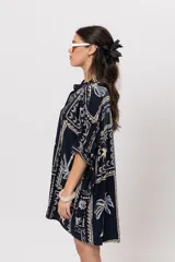 Camisa oversize azul marino con estampado de motivos marinos, palmeras y elementos geométricos en tonos claros. Presenta cuello mao y cierre frontal de botones.