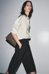 Bermuda larga color marrón oscuro, de tiro medio con cintura con trabillas. Presenta bolsillos laterales ocultos en la costura y detalle de raya planchada. Cierre frontal con cremallera, botón y ganchos metálicos.