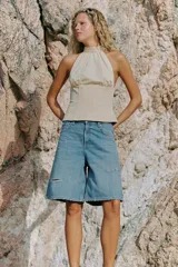 Top halter combinado con cuello subido ajustable mediante botones y hombros descubiertos, de diseño bicolor en tonos beige y blanco con sutiles rayas verticales.