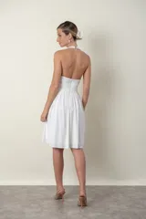 Vestido corto blanco de fiesta, con escote halter, drapeado en la cintura y falda con vuelo.