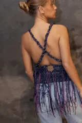 Top tejido artesanal de silueta suelta, con breteles anchos y escote halter. Diseño calado con flecos largos multicolores que aportan movimiento y textura.