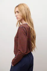 Remera de manga larga con diseño de rayas horizontales en azul y blanco, destacada por un cuello redondo en color bordó con costuras a la vista.