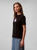 Remera Calvin Klein de algodón negro, de corte regular y manga corta con vuelta. Cuenta con cuello redondo y diseño gráfico con el monograma de la marca en un cuadro con degradado de colores rosado y celeste en el pecho.