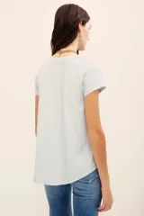Remera básica de corte holgado, color negro, con mangas cortas y cuello redondo. Presenta un diseño con largo irregular y ruedo redondeado, confeccionada en algodón peruano con textura jaspeada.