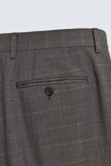 Pantalón de traje de corte regular fit, confeccionado en lana de origen italiano. Presenta un diseño a cuadros sutiles, bolsillos delanteros, bolsillos traseros de doble vivo con botón y cierre frontal con cremallera y botón.