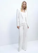Chaqueta tipo americana de diseño estructurado y corte recto, color blanco. Presenta cuello con solapas de muesca, cierre frontal con un botón, mangas largas con puños abotonados y dos bolsillos de parche frontales. Incluye forro interior.