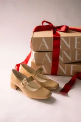 Zapato de charol negro con hebilla metálica ajustable y taco cuadrado.