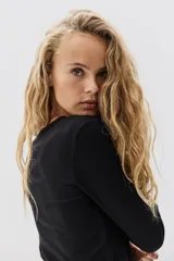 Remera negra de manga larga, corte ajustado al cuerpo, con cuello redondo y tejido de punto acanalado.