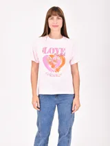 Remera de algodón color rosa claro, con cuello redondo y mangas cortas. Presenta un estampado frontal con la palabra 'LOVE' y un diseño de corazones en tonos rosa y naranja con frases motivacionales.