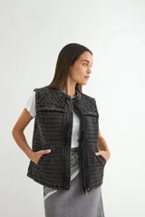Chaleco de denim acolchado con efecto lavado, diseño sin mangas, cierre frontal y bolsillos laterales.
