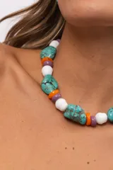 Collar corto compuesto por cuentas grandes de piedra turquesa irregular, alternadas con cuentas circulares blancas, naranjas y lilas.