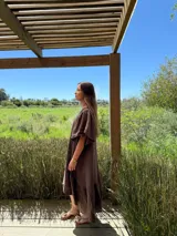 Vestido verde oliva de lino, corte suelto, con mangas abullonadas y volado en el ruedo.