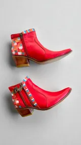 Botas cortas de cuero rojo con detalles pintados a mano en tonos dorados y turquesa en el talón, taco cuadrado de madera y punta fina. Cuentan con cierre lateral y diseño exclusivo de Carolina De Cunto.