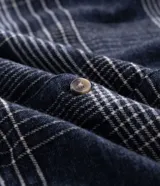 Camisa de manga larga confeccionada en franela de algodón, con cuello bowling y cierre frontal de botones. Presenta un diseño de estampado a cuadros en tonos marrones y beige, con un corte regular tradicional.