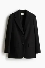 Blazer largo de color negro con solapas de muesca, hombreras y bolsillos delanteros ribeteados con solapa. Presenta un diseño de botonadura sencilla con dos botones frontales y abertura con botón en los puños.
