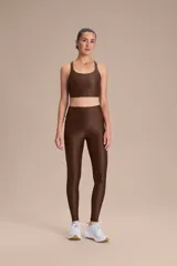 Top deportivo de compresión media con diseño de espalda cruzada, confeccionado en tejido técnico con textura acanalada y acabado brillante. Cuenta con copas removibles y protección UV 50+.