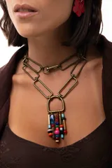 Collar de cadena con eslabones rectangulares en tono bronce, diseñado para ser versátil y usarse largo o doble. Presenta un dije central en forma de herradura del que cuelgan múltiples cuentas de colores variados y piezas metálicas cilíndricas.