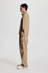 Campera deportiva color beige en tejido sherpa, con cuello alto, cierre frontal, bolsillo superior con cierre, bolsillos laterales con cierre, puños y bajo con elástico fino.