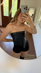 Top strapless negro de ecocuero con tachas plateadas en el borde superior.