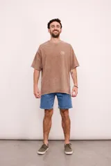 Remera verde militar de corte oversize con cuello redondo y estampado en la espalda con el logo de Brixton, una flor de hibisco y la frase "Where hibiscus grows, peace flows".